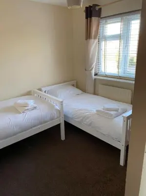 two white beds in a room with a window at Comfortable 3 bed house in Chelmsford in Chelmsford