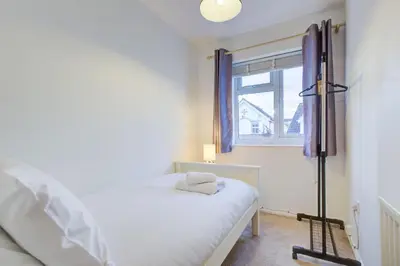 a bedroom with a white bed and a window at Comfortable 3 bed house in Chelmsford in Chelmsford