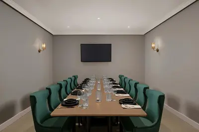 a conference room with a long table and green chairs at Delta Hotels by Marriott Colchester in Colchester