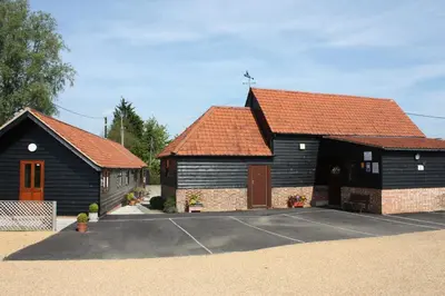 two barns with red roofs in a parking lot at Puttocks Farm in Great Dunmow