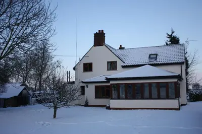 a white house with snow on the ground at Puttocks Farm in Great Dunmow