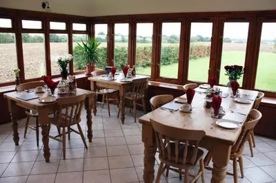 a dining room with tables and chairs and windows at Puttocks Farm in Great Dunmow