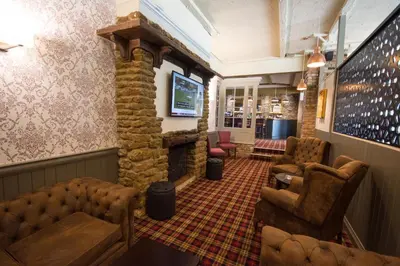 a waiting room with a stone fireplace and chairs at Dragonfly Hotel Colchester in Colchester
