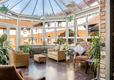 a conservatory with couches and chairs and windows at Dragonfly Hotel Colchester in Colchester