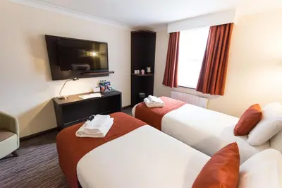 a hotel room with two beds and a flat screen tv at Dragonfly Hotel Colchester in Colchester