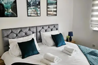 a bedroom with a large white bed with blue pillows at BSE Homes & Properties Ltd 4-Bedroom Home, Harlow , with Parking sleeps 6 in Great Parndon