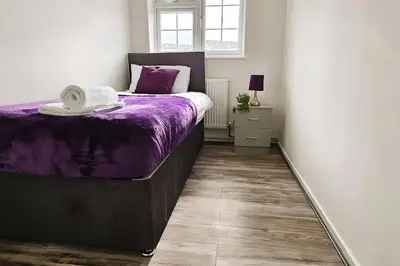 a bedroom with a bed with a purple blanket at BSE Homes & Properties Ltd 4-Bedroom Home, Harlow , with Parking sleeps 6 in Great Parndon
