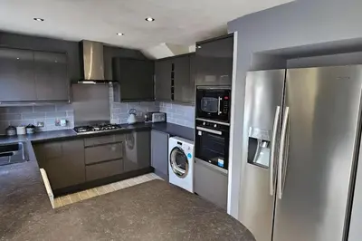 a kitchen with a stainless steel refrigerator and a dishwasher at BSE Homes & Properties Ltd 4-Bedroom Home, Harlow , with Parking sleeps 6 in Great Parndon