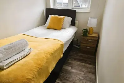 a bedroom with a bed with a yellow blanket at BSE Homes & Properties Ltd 4-Bedroom Home, Harlow , with Parking sleeps 6 in Great Parndon