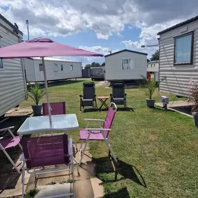 a table and chairs under an umbrella in a yard at Sunshine Atlas Glamping Retreat in Jaywick Sands