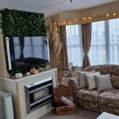 a living room with a couch and a flat screen tv at Sunshine Atlas Glamping Retreat in Jaywick Sands