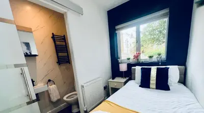 a bedroom with a bed with blue walls and a window at Welcome to Northview House Stylish 4 Bedroom Home in Southend by Jesswood Properties Contractors Corporates Relocation Stays Long Stays Welcome in Southend-on-Sea