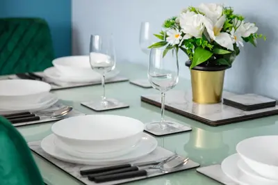 a table with plates and glasses and a vase of flowers at Welcome to Northview House Stylish 4 Bedroom Home in Southend by Jesswood Properties Contractors Corporates Relocation Stays Long Stays Welcome in Southend-on-Sea