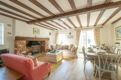 a living room with a table and a fireplace at Harvest Cottage in Aldeburgh