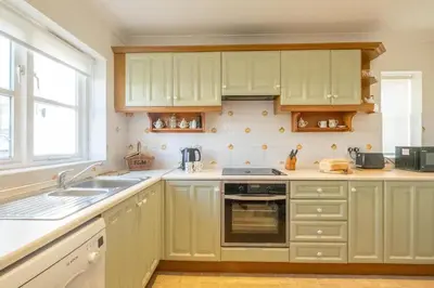 a kitchen with green cabinets and a sink and a window at Harvest Cottage in Aldeburgh