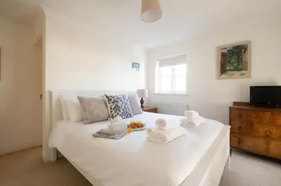 a bedroom with a white bed with towels on it at Harvest Cottage in Aldeburgh