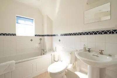 a white bathroom with a toilet and a sink at Harvest Cottage in Aldeburgh