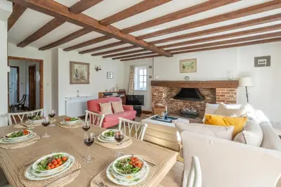 a living room with a table and a fireplace at Harvest Cottage in Aldeburgh