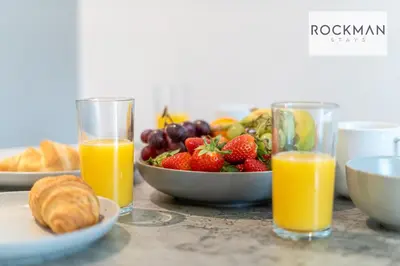 a table with a bowl of fruit and two glasses of orange juice at Royal Oak Apartments 1 - Free Van Parking - 2 Bedroom Apartment - 2 bathrooms - Sleeps 6 - Perfect for Contractors - Fast Wi-fi in Brentwood