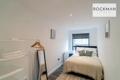 a white bedroom with a bed and a window at Royal Oak Apartments 1 - Free Van Parking - 2 Bedroom Apartment - 2 bathrooms - Sleeps 6 - Perfect for Contractors - Fast Wi-fi in Brentwood