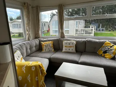 a living room with a gray couch with pillows at D34 Steeple Bay Caravan Site in Chelmsford