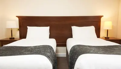 a hotel room with two beds and two lamps at White Hart Hotel by Greene King Inns in Braintree