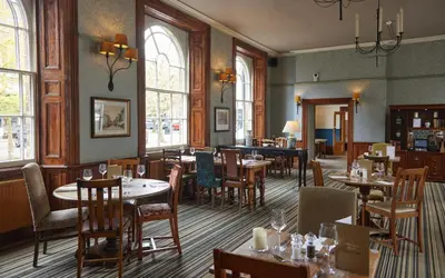 a restaurant with tables and chairs and windows at White Hart Hotel by Greene King Inns in Braintree