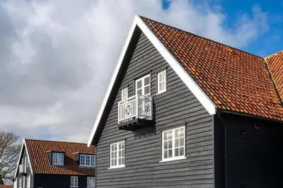 a black house with a white roof and a balcony at 4 Truman Lodge in Thorpeness