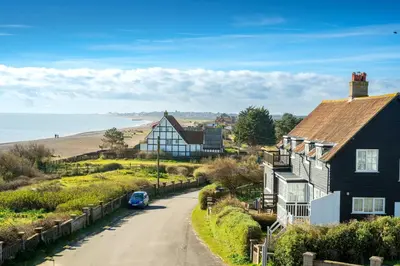 a house on the side of a road next to a beach at 4 Truman Lodge in Thorpeness