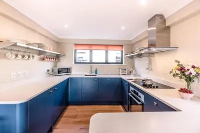 a kitchen with blue cabinets and a window at Melody Cottage in Aldeburgh