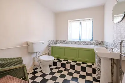 a bathroom with a green tub and a toilet and a sink at Melody Cottage in Aldeburgh