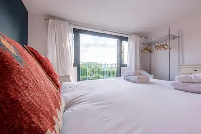 a bedroom with a large white bed with a large window at Melody Cottage in Aldeburgh