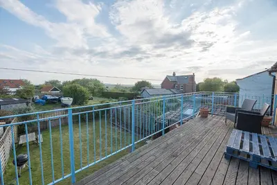 a balcony with a blue railing on a wooden deck at Melody Cottage in Aldeburgh
