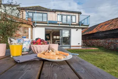 a table with a plate of bread and a glass of orange juice at Melody Cottage in Aldeburgh