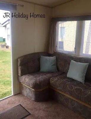 a couch in a living room with a window at J.R. Holiday Homes in Clacton-on-Sea