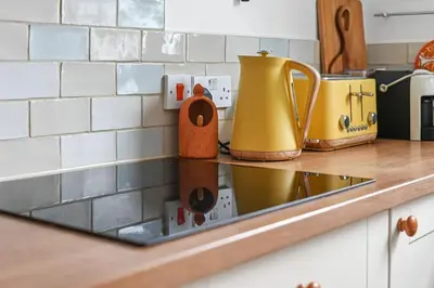 a kitchen counter with a stove with a yellow kettle at St John's Corner Cottage, Bury St. Edmunds in Bury Saint Edmunds