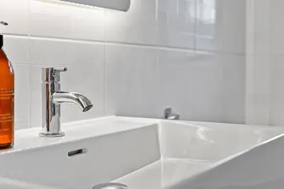 a sink with a soap bottle next to a sink at St John's Corner Cottage, Bury St. Edmunds in Bury Saint Edmunds