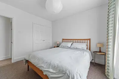 a white bedroom with a bed and two lamps at St John's Corner Cottage, Bury St. Edmunds in Bury Saint Edmunds