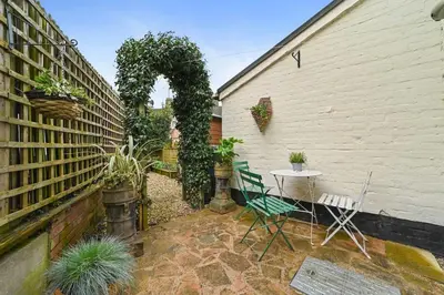 a patio with a table and chairs next to a building at St John's Corner Cottage, Bury St. Edmunds in Bury Saint Edmunds