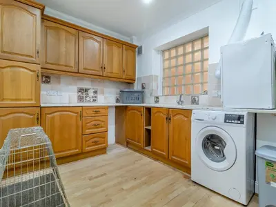 a kitchen with wooden cabinets and a washer and dryer at The Great Escape in Ipswich