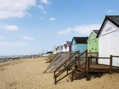 a row of colorful beach huts on a sandy beach at Forest Retreat in Saxmundham
