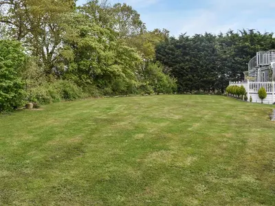 a large field of grass in front of a house at Forest Retreat in Saxmundham