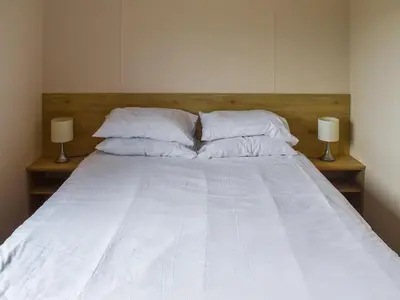 a bed with white sheets and pillows and two lamps at Forest Retreat in Saxmundham