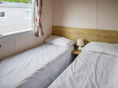 two beds in a room with a window at Forest Retreat in Saxmundham