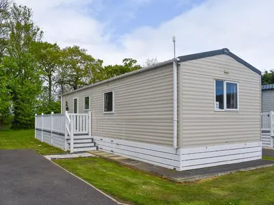 a small white building with a porch on a yard at Forest Retreat in Saxmundham
