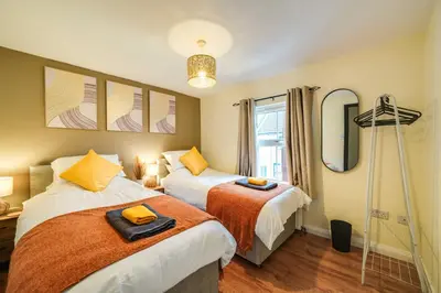 a bedroom with two beds and a mirror at Stylish Victorian house, close to City Centre in Colchester
