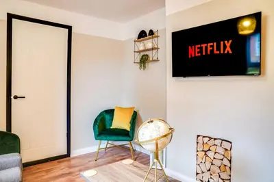 a living room with a green chair and a sign that reads netflix at Stylish Victorian house, close to City Centre in Colchester