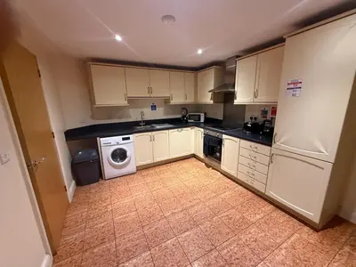 a kitchen with white cabinets and a washer and dryer at Comfort Arena in Colchester