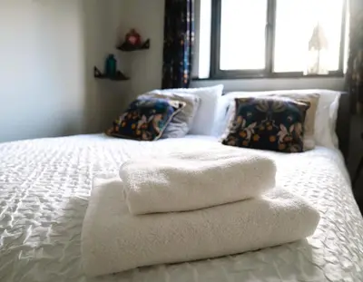 a white bed with towels on it with a window at Urban Oasis in Billericay