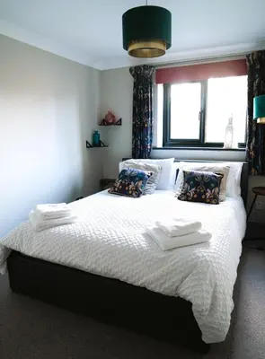 a bedroom with a large bed with white sheets and pillows at Urban Oasis in Billericay